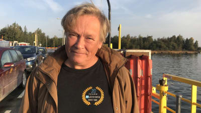 Kvinna i medelåldern klädd i svart tröja och brun jacka ombord på en färja.