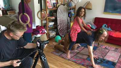 En person filmar ett barn som sitter på sin pappas rygg och ler