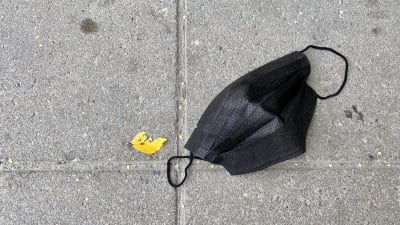 Maassa on kasvomaski, sen vierellä keltainen koivunlehti.