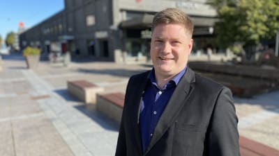 Mansantagen person poserar på torg.