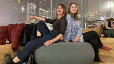 Två kvinnor sitter på en stor dyna. Tea Auramo och Laura Rusanen