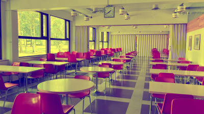 En tom sal med röda stolar och runda bord.