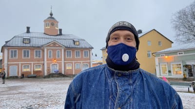 Petteri står iklädd ett munskydd och ler i Borgå gamla stad.