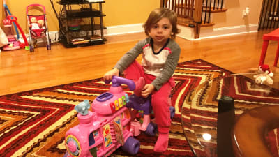 Tvååriga Elyana kör sin leksaksmoped hemma i vardagsrummet i Philadelphia.