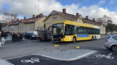 En gul buss som krockat med en bil.
