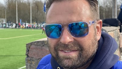 Ung man med solglasögon bredvid fotbollsplan i Pargas. 