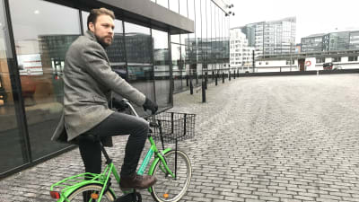 LO:s Mads Busck på cykel med Islands Brygge i Köpenhamn i bakgrunden.