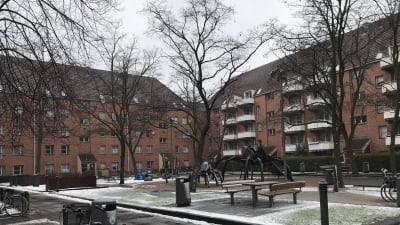 En innergård med två röda tegelhus och vita balkonger.