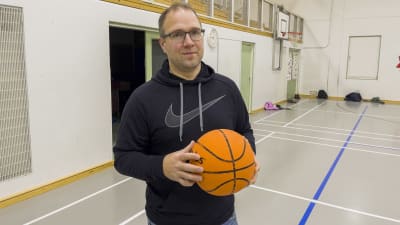 En man håller i en basketboll inne i en gymnastiksal. Gymnastiklärare Kaj Hagman.