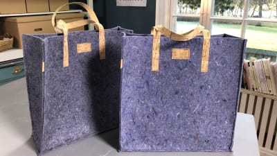 två väskor sydda av lumpfilt står på ett bord