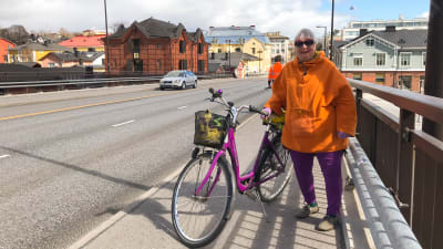 En kvinna med sin cykel på Mannerheimgatans bro.