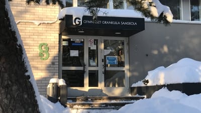 Gymnasiet Grankulla Samskola, fasaddörr med snödrivor i vintersol.
