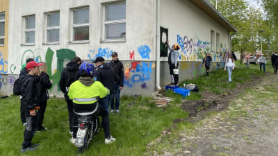 Ungdomar målar gammal skolbyggnad med sprejfärg.