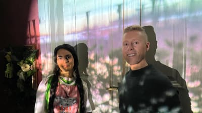 Niklas Aldén och Nayab Ikram poserar framför en vägg som belyses med en bild från en camera obscura.
