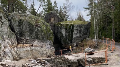 Grottans ingång i Gumbostrand i Sibbo. Orange stängsel framför. 