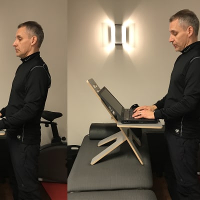En man står vid sin laptop som ligger på ett litet bord. Bordet i sin tur står på en bänk så mannen får en optimal ståend arbetsställning.