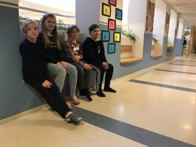 Elever sitter i skolans korridor. 