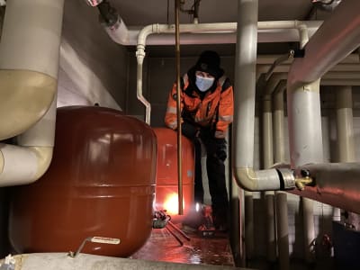 30-vuotias putkiasentaja Jesse-Petteri Raunio vaihtaa Vilppulan paloaseman lämpökeskuksen paisuntasäiliötä. Työ on tehtävä kyyryssä, koska paikka on ahdas