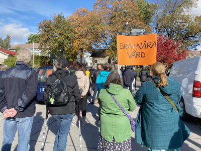Demonstration, två kvinnor håller upp ett plakat med texten Bra + nära vård.