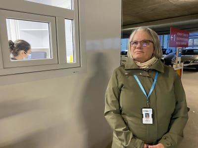 Ylihoitaja Maiju Manelius seisoo näytteenottokontin edessä TYKSin T-sairaalan pysäköintihallissa. 