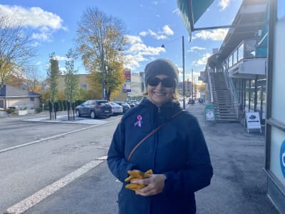 En kvinna i solglasögon och höstkläder. Hon står i en stad och ler mot kameran.