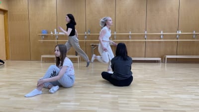 Fyran flickor dansar i en gymnastiksal. 