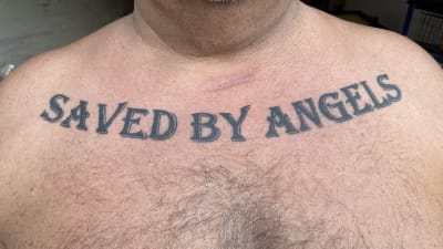 Tatuering på en mans bröst: "Saved by Angels".