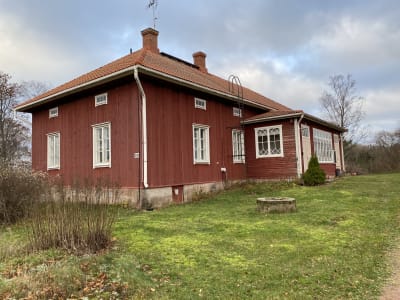 Rött gammalt trähus med vita knutar.