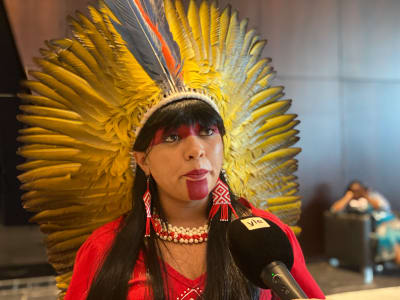 Kvinna och kongressledamot från ursprungsbefolkning i Amazonas, med huvudbonad med stora gula fjädrar