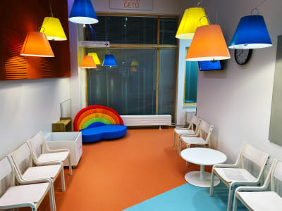 Vänterum för barn, liten soffa med regnbågsryggstöd, lampskärmar i olika färger och texten Getö på väggen.