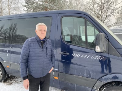 En äldre man bredvid en taxi i skåpbildsmodell.
