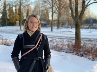 En ljushårig kvinna intill en snöig gata.