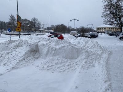 Snöhögar intill en parkering och en väg.