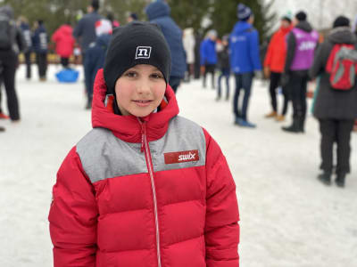 En pojke i vinterkläder framför en folksamling.