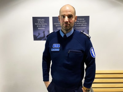 Patrik Karlsson iklädd polisens kontorsuniform tittar in i kameran med händerna i fickorna.