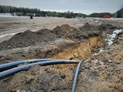 Vatten- och avloppsrör går ner i en grop i jorden på en åker i Degerby.