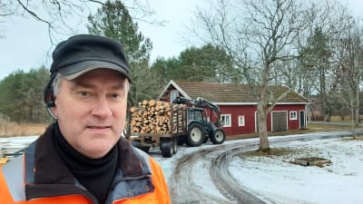 Man framför skogsbil och stock på en gammal gård i Täktom, Hangö.