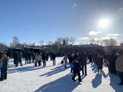 Många tiotals människor går omkring på Kaserntorget i Vasa för att titta på försvarsmaktens materielutställning. Solen lyser från blå himmel.