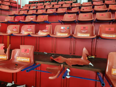 Förstörda röda läktarstolar i ishockeyarena. 