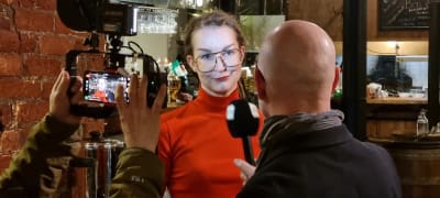 Kvinna blir intervjuad av journalist och fotograf för Yles tv.