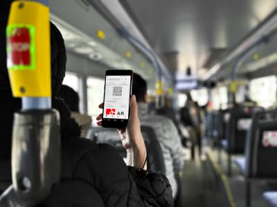 En person ser på sin mobiltelefon, som visar en nätsida med en bussbiljett.