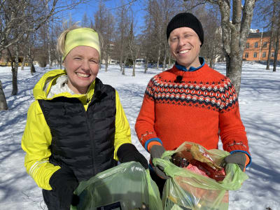 Kaisu Paulanto ja Nicke Aldén katsovat hymyillen kameraan. Käsissään vihretä roskapussit täynnä roskaa.