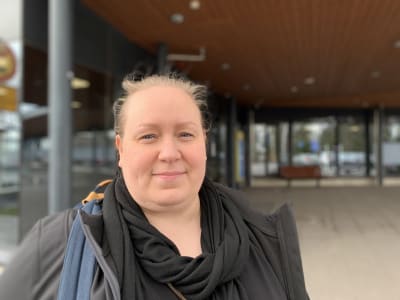 Personporträtt på kvinna som ler och tittar in i kameran. Hon står utanför sjukhusentré.