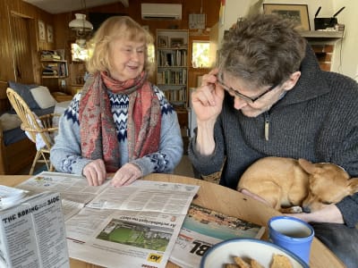 En man och en kvinna som sitter vid kaffebordet och läser en dagstidning.