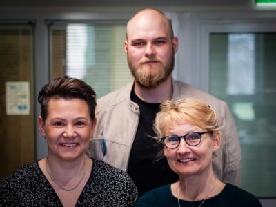 Två kvinnor och en man poserar för ett porträttfoto