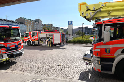 Tre brandbilar framför parkeringsanläggningen Toriparkki i Lahtis. En brandman fixar med något vid en av brandbilarna.