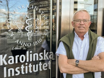 Peter Strang står och ler framför en dörr till Karolinska institutet.