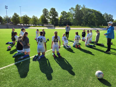 Ett juniorlag i vita kläder värmer upp på fotbollsplan.