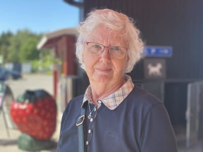 En äldre kvinna utanför en affär.