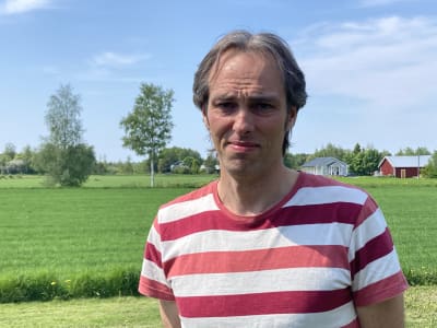 Kenneth Nordberg i randig t-skjorta står framför ett grönt åkerfält.